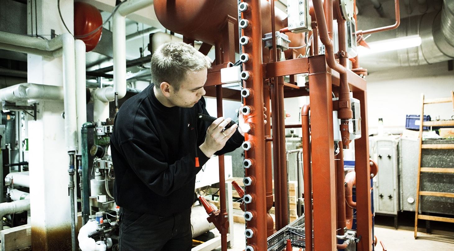 Billedet viser en person som arbejder på et ammoniak anlæg. Anlægget anvendes bla. ifm. kurser på Teknologisk Institut.